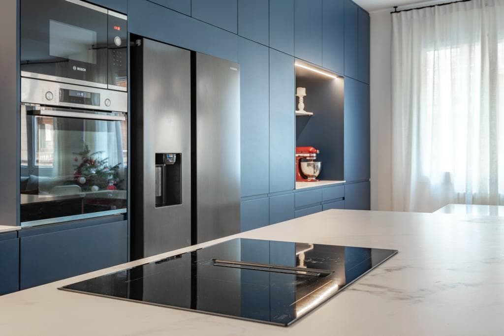 Encimera Calacatta con isla y fregadero en una cocina de frentes azules